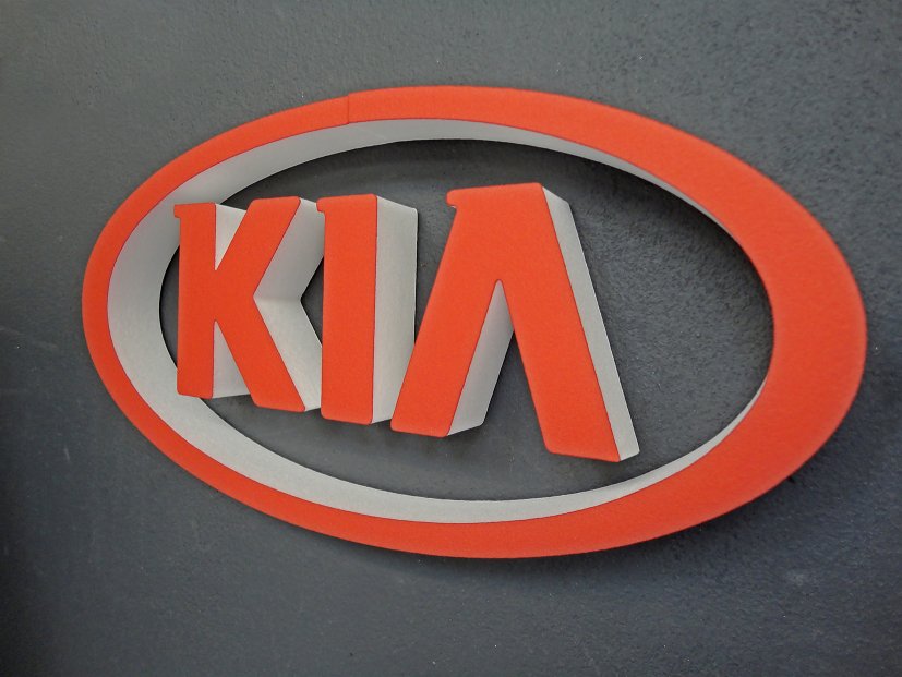 3D-KIA Logo Schriftzug aus XPS-Schaum lackiert und mittels Magnetplättchen an grauer Eisenfarbenwand flexibel befestigt.